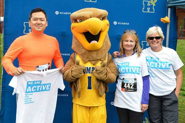 Humber mascot standing with three people who have We Are Active shirts