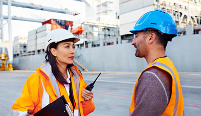 man and woman standing with safety hats on talking