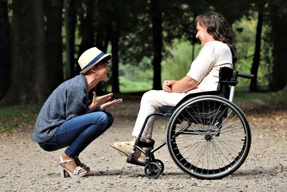 one person speaking to another person sitting in a wheelchair.