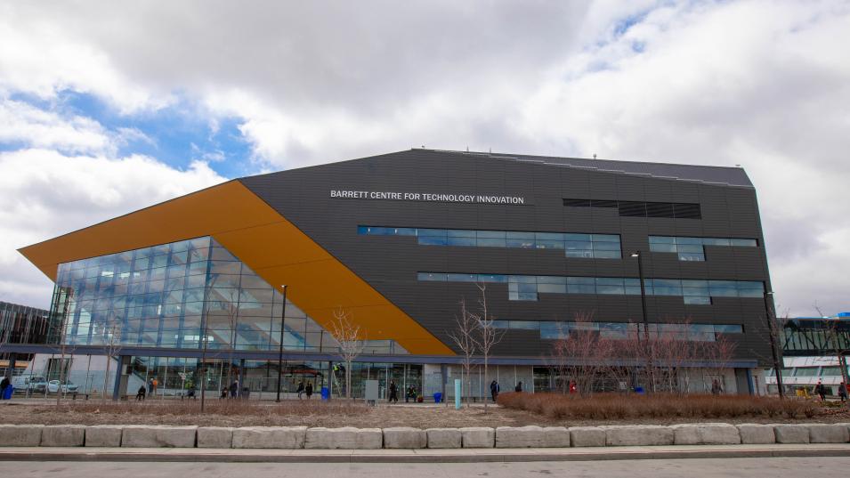 The Barrett CTI building from across the parking lot. The building is grey with orange and glass accents