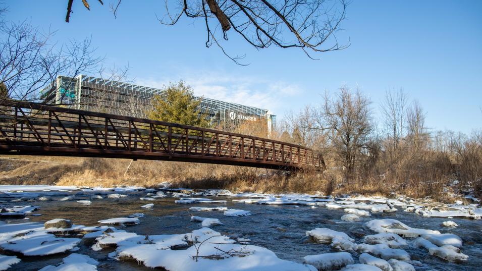 The LRC building on Humber's North campus, seen from the snowy shore of the Humber River with a bridge in the foreground
