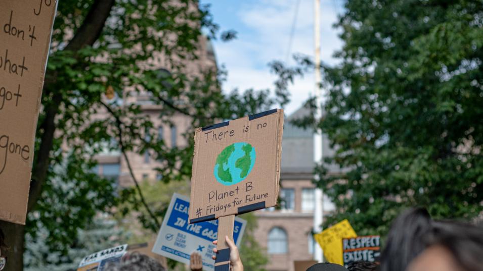 People at a Climate Strike march fill a city street, holding protest signs. One of them says: "There is no Planet B"