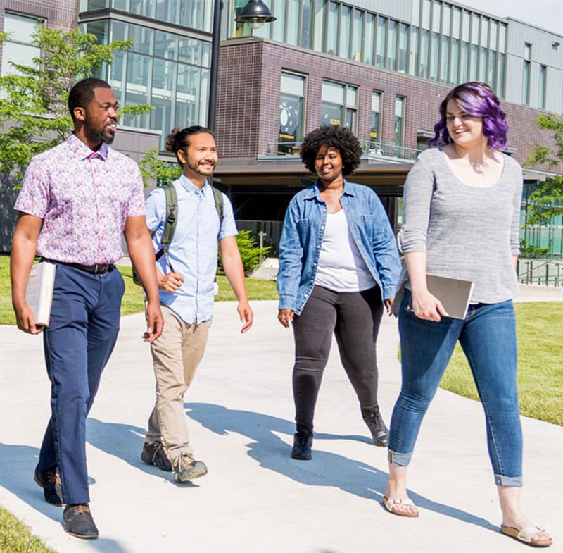 Four students walking on campus in the spring