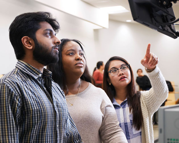 Three students looking at computer monitor