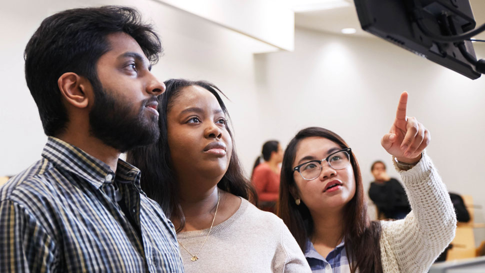 Three students looking at monitor