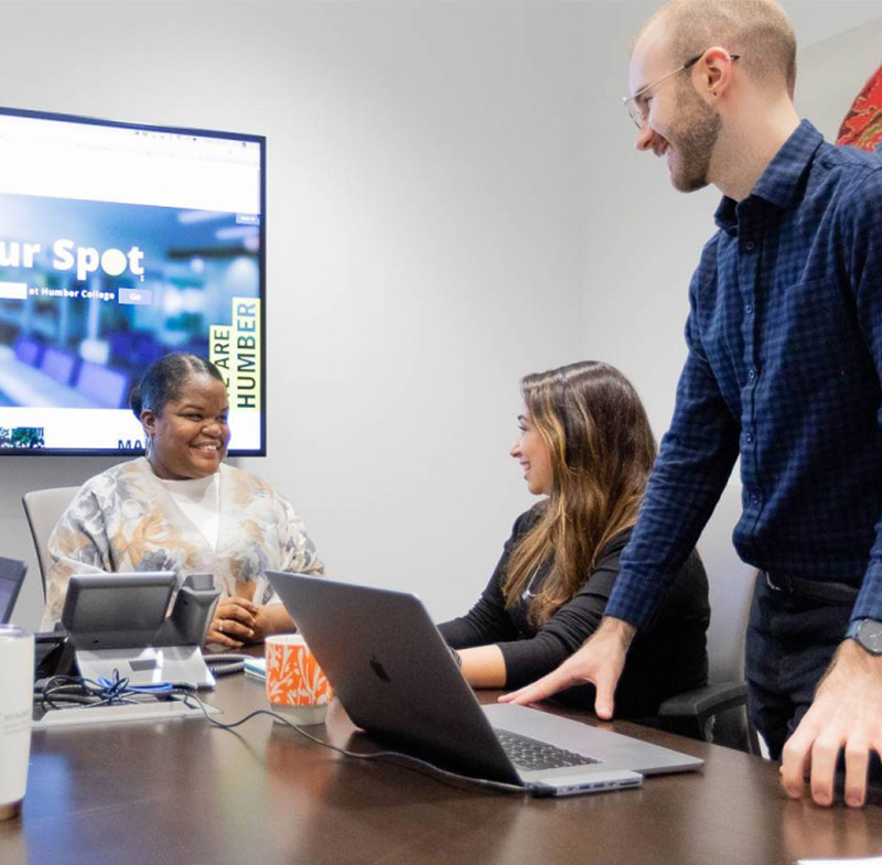 People seating around a conference table with a presentation on a screen