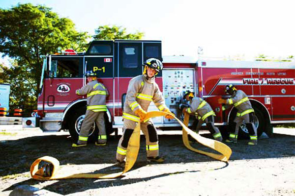 Fire truck with fireman around it using fire hose