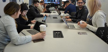 Group of men and women with laptops gathered at a long table