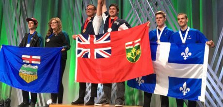 Students on stage holding provincial flags