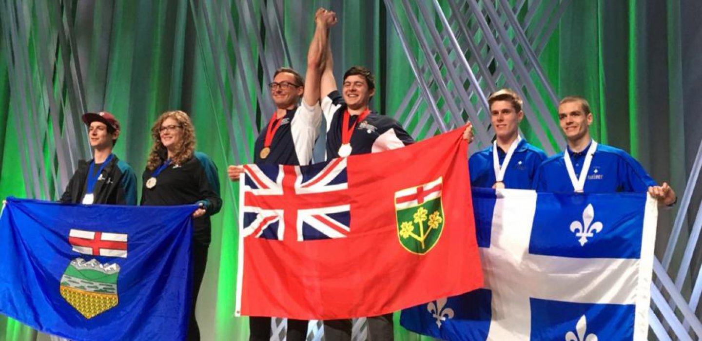 Students on stage holding provincial flags