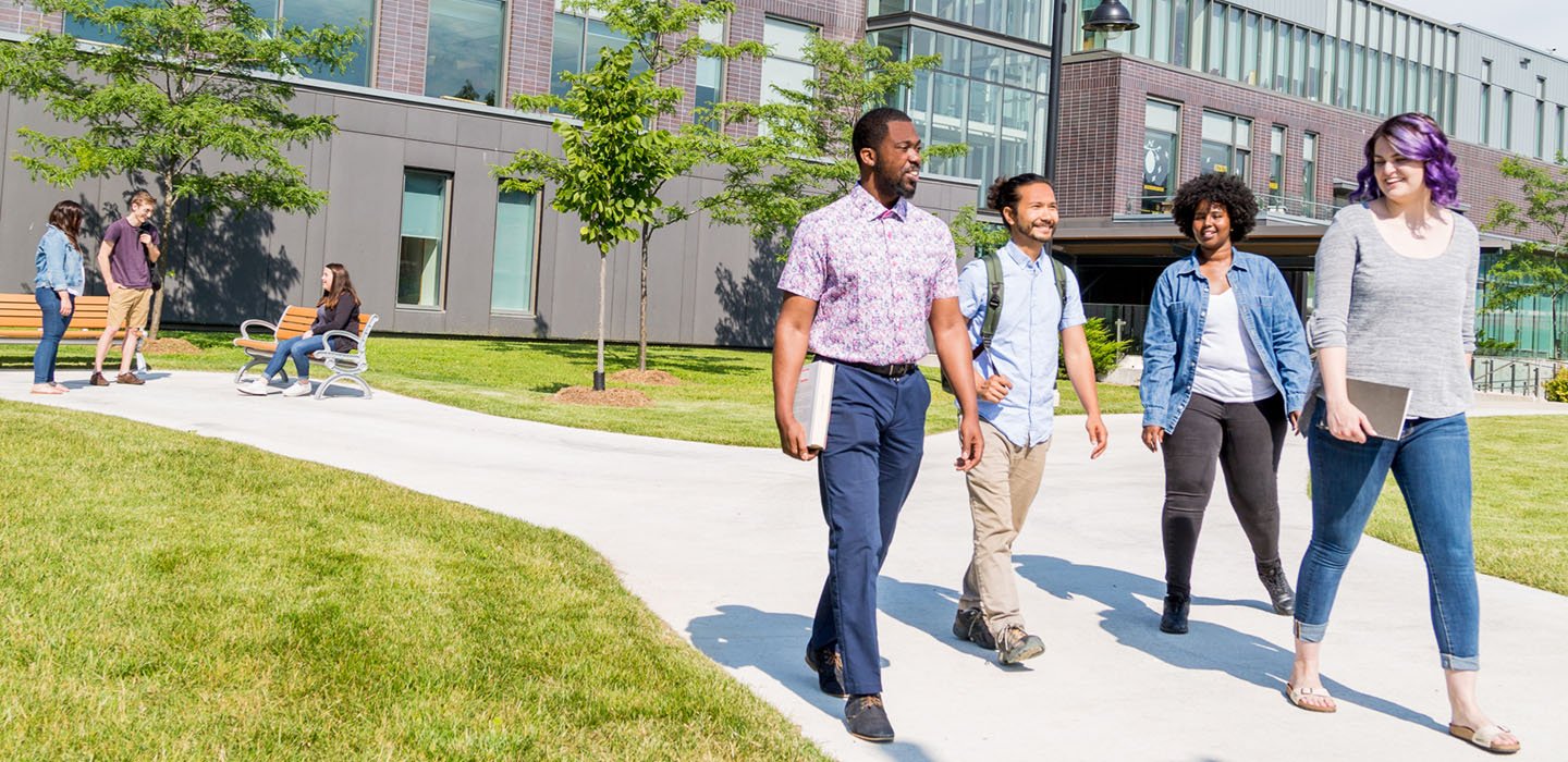Four students walking on campus in the spring