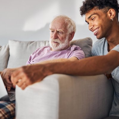 Elderly individual with their caregiver looking at laptop