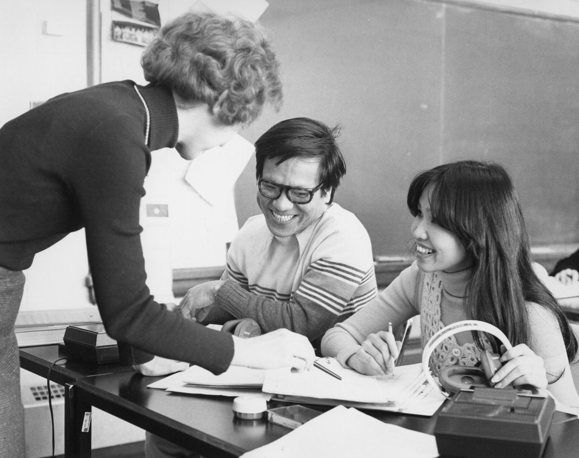 1970s- A faculty member works with International students in an English as a Second Language classroom. Notice the cassette tape players and headphones in the photo.