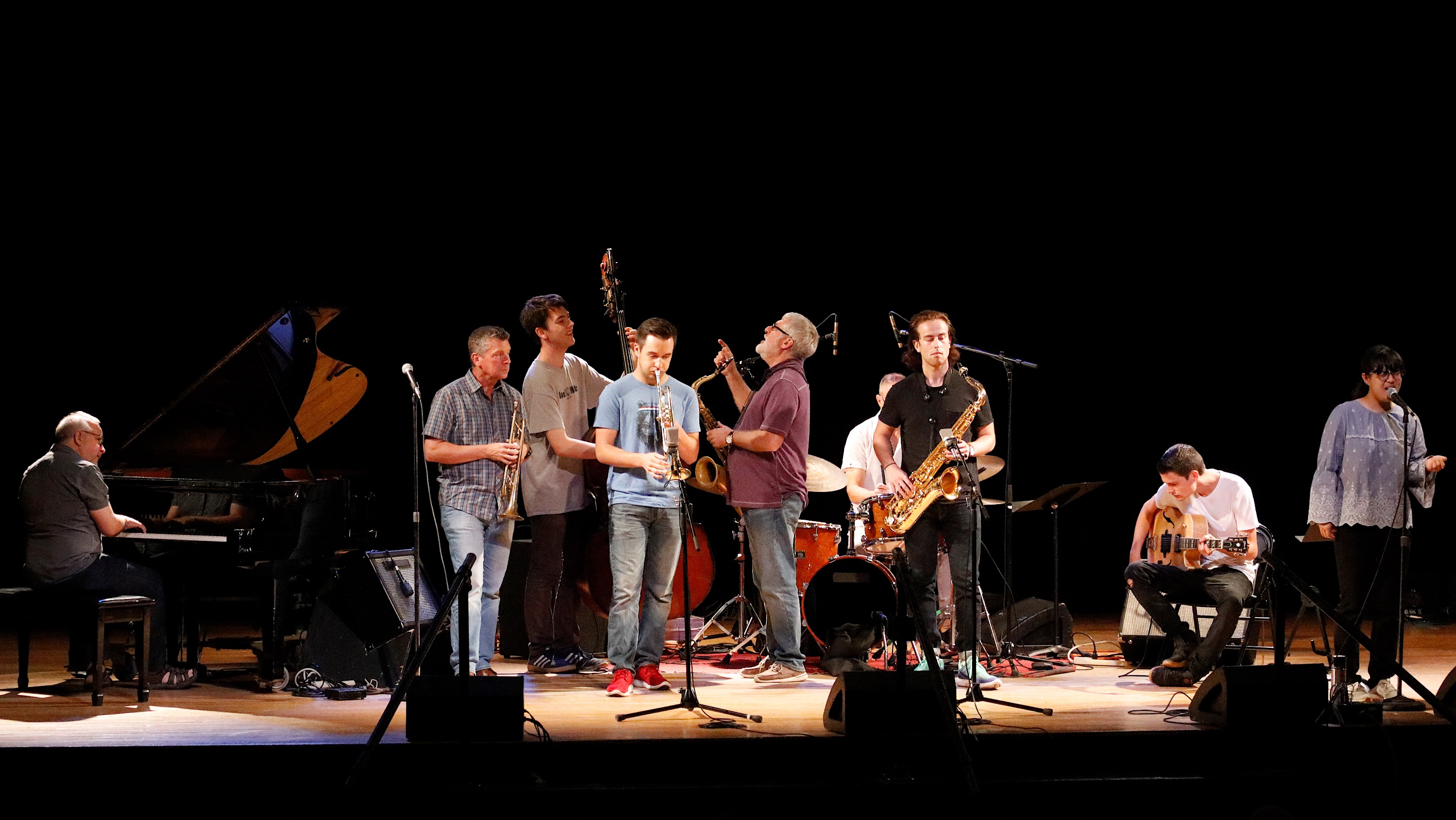 Group of student jazz musicians performing on stage with their faculty