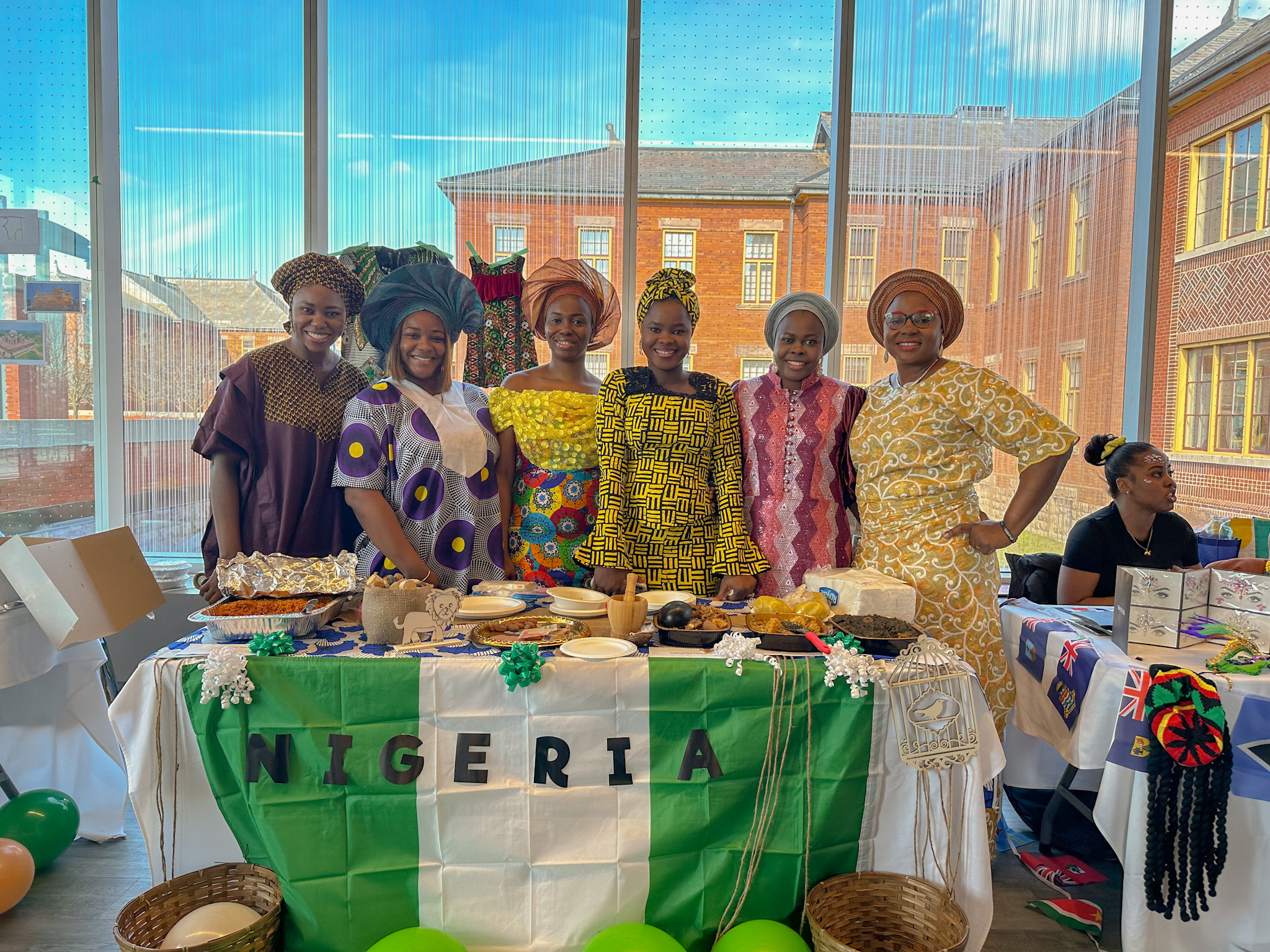 Group of women in traditional Nigerian dress standing behind a table