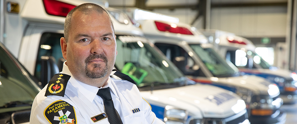 Alumnus Lawrence Saindon standing in front of a row of paramedic vehicles.