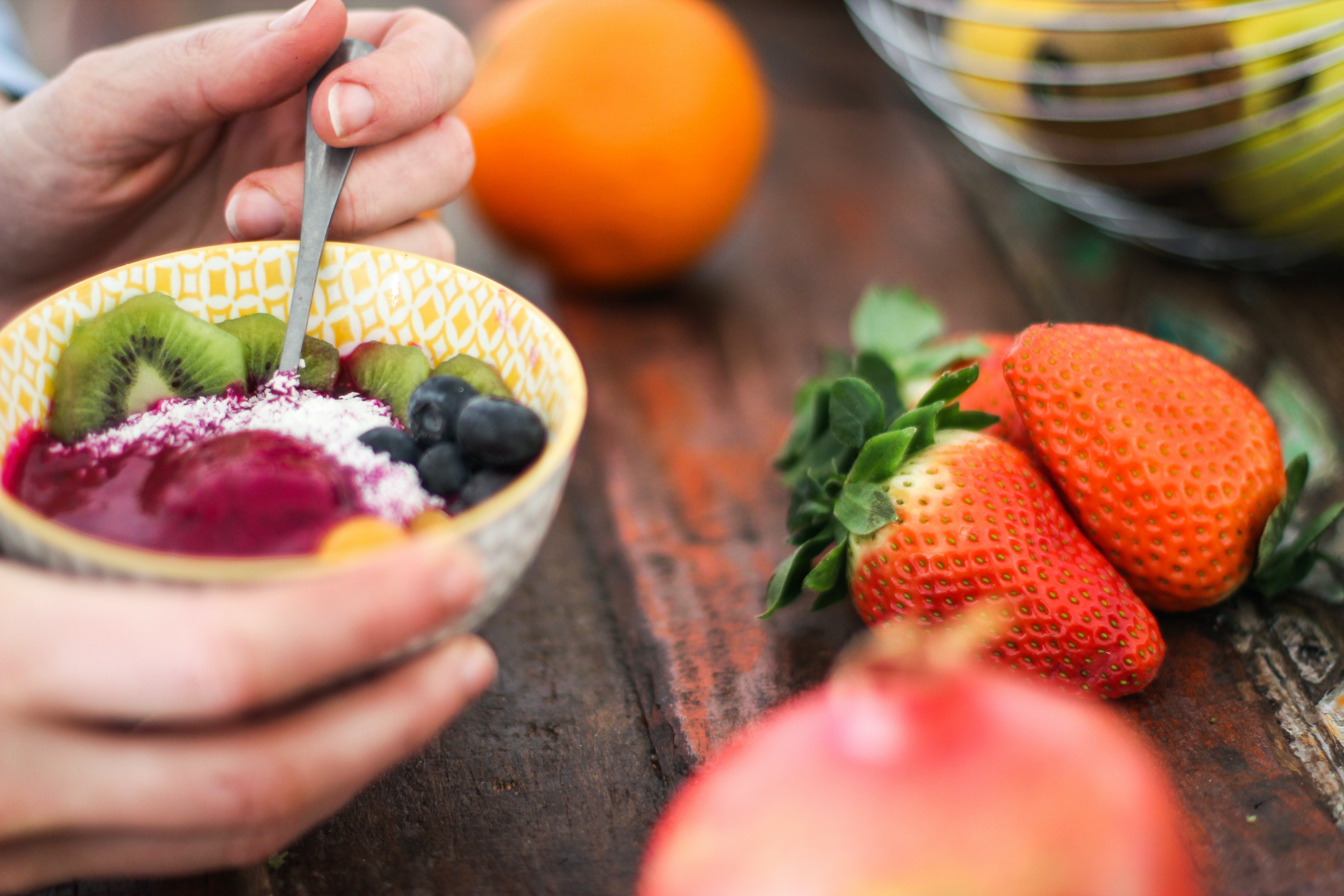 Person holding fruit salad in a bowl.