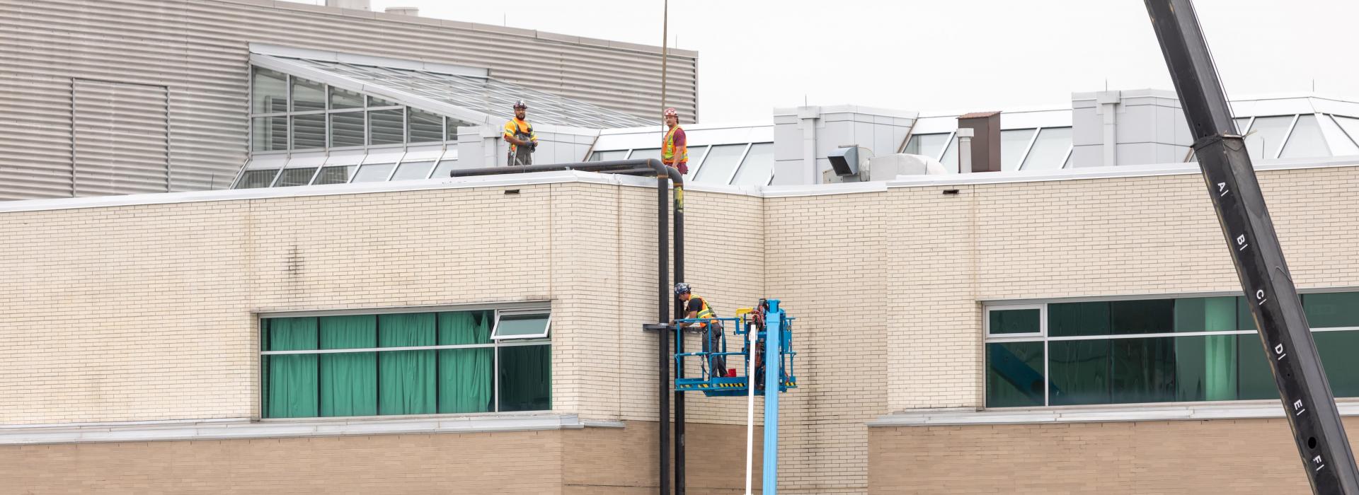 Workers on roof of Guelph Humber building installing pipes