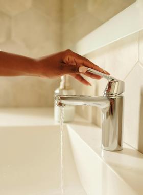 Hand reaching faucet and tap running