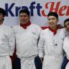 Four individuals stand arm-in-arm wearing chef uniforms.