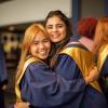 Two people wearing graduation gowns embrace at Humber College’s Fall Convocation.