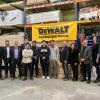 A group of people stand underneath a sign that reads DEWALT Guaranteed Tough.