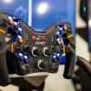 A closeup shot of a steering wheel with various buttons on knobs on it from a racing simulator.