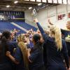 Athletes stand together in a huddle in a gym.