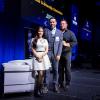 Three people stand together on a stage.