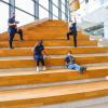 Students sit on the giant yellow staircase in the atrium of the Barrett CTI, distanced by at least 2 metres and wearing masks
