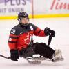 Claire Buchanan is suited up with helmet, pads and uniform, playing sledge hockey