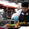 A person plates a dish while cooking in a kitchen.