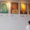 Individual looks up at framed portraits on a wall. 