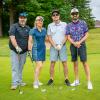 Four people wearing golfing attire stand together on a golf course.