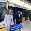 Several people stand in front of an LRT train and behind a podium that reads Building Ontario.