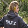 Alexandra Kaske has her back to the camera, looking over her right shoulder. Her sweatshirt says "POLICE foundations." 