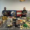 Two people stand amongst a miniature city made of LEGO.