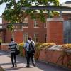 Two students walk together past a building.