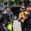 A police officer holds up a speed camera as youth look on.