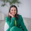 A smiling person sits on a chair.