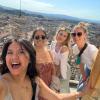 Four students smile and take a selfie with an Italian city in the background.