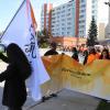 One person holds a flag as two others carry a banner that reads Walk for Reconciliation.