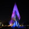 The exterior of a building at night that has the colours blue and purple being projected onto it.