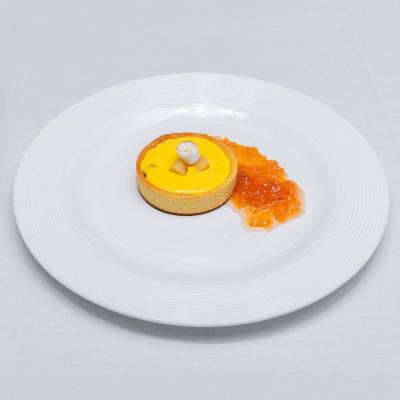 A dessert sits on a white plate and is accompanied by what looks like an orange jelly.