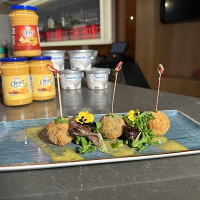 A dish of three croquettes on a plate with Kraft Heinz products behind them.