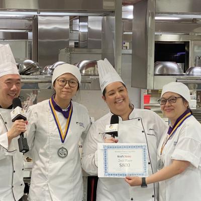 Two people are joined by two others wearing chef outfits holding up a certificate that reads 2nd Place.