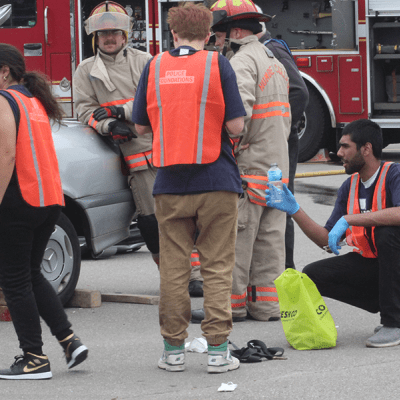 A student who’s crouching down looks at a water bottle they picked up.