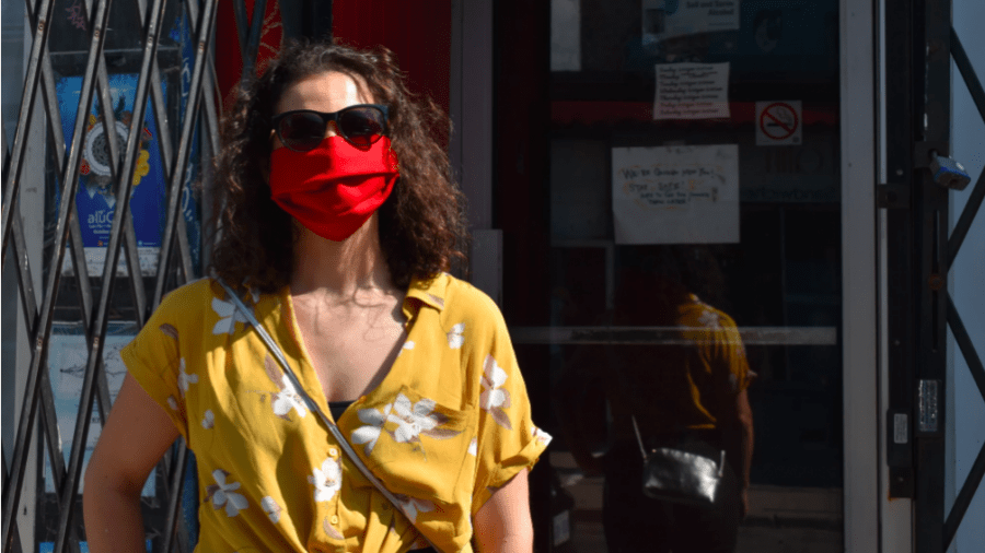 A Kensington Market visitor colour coordinates their red mask with their yellow shirt