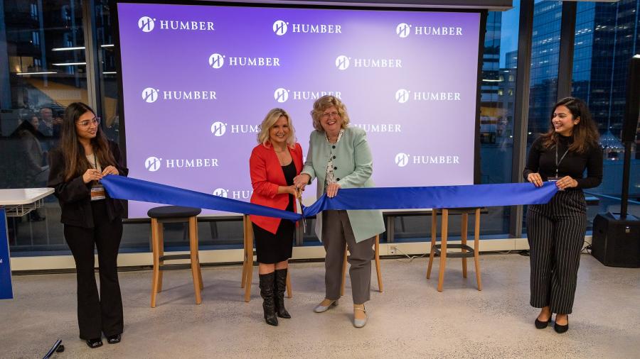 Two people cut a ribbon while standing in front of a screen with the Humber College logo on it.