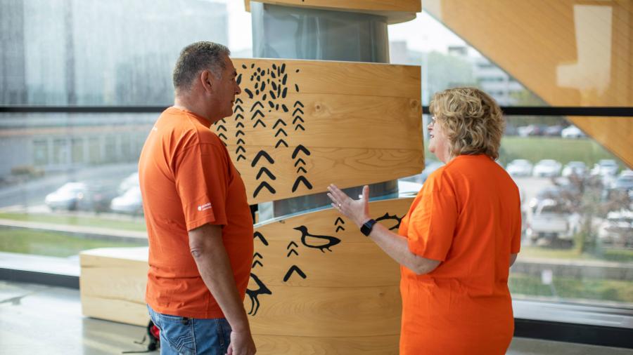 Jason Seright and Ann Marie Vaughan engage in a conversation while wearing orange shirts for Orange Shirt Day.